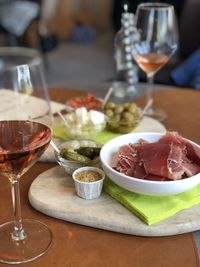 Close-up of food on warm wooden table, rosé wine and tapas with meat, olives and cheese