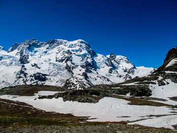 Scenic view of snowcapped mountains against clear blue sky