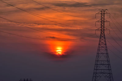 Low angle view of silhouette electricity pylon against sky during sunset