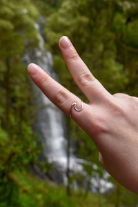 Cropped hand of woman gesturing peace sign in forest