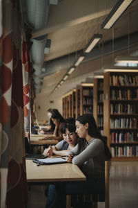 Professor and student discussing over book in library at university