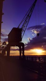 Silhouette people at commercial dock against sky during sunset