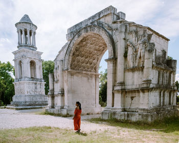 Woman standing by historical building against sky