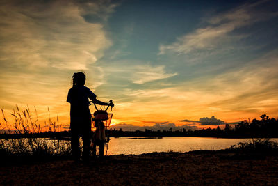 Silhouette man standing on beach against sky during sunset