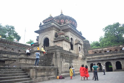 People in front of historic building against clear sky