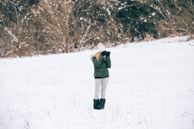 Woman photographing while standing on snow field