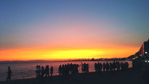 Silhouette people on beach against clear sky during sunset