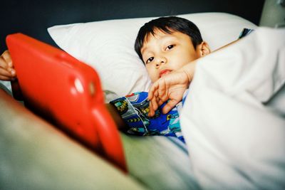 Portrait of cute boy lying on bed at home