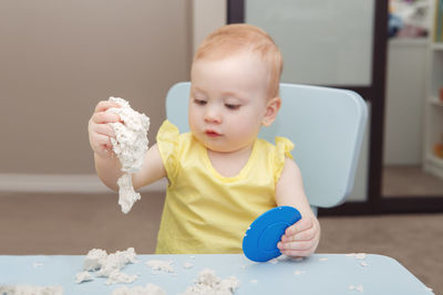 Cute baby girl holding table at home