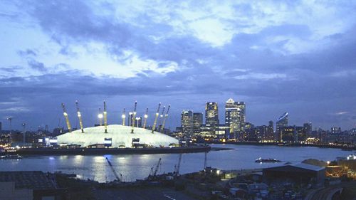 View of illuminated cityscape against cloudy sky