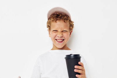 Portrait of smiling boy gesturing against white background