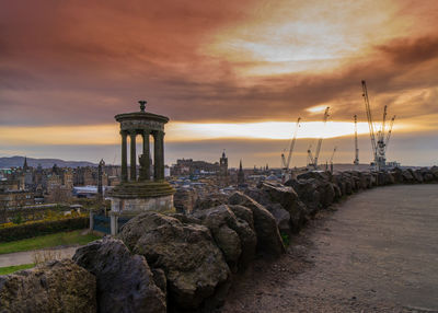 Built structure by sea against sky during sunset