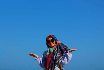 Low angle view of man standing against clear blue sky