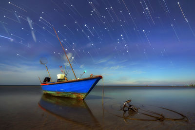 Fishing boat at beach against sky at night