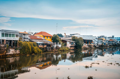Reflection of houses and buildings in lake against sky