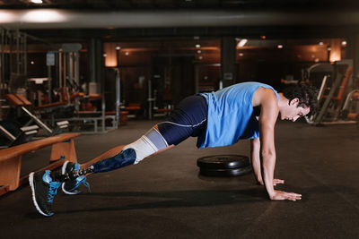 Full length of man with prosthetic legs exercising in gym