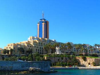 View of building by sea against clear blue sky