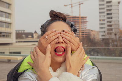 Woman covering friend eye on building terrace