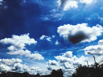 Low angle view of silhouette trees against blue sky