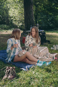 Smiling friends sitting at campsite in forest