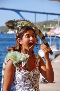 Close-up of young woman with iguana on her head and shoulder