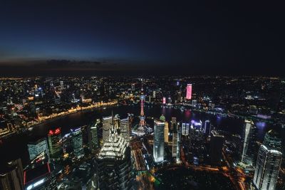 High angle view of illuminated city buildings against sky at night