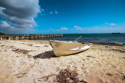 Boat moored on beach against sky