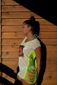 Young woman looking away while standing on wood