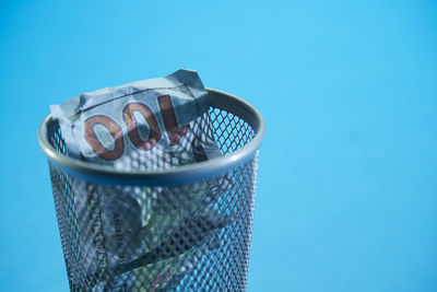 Close-up of garbage can against blue background