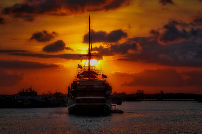 Ship in sea against cloudy sky during sunset