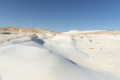 Scenic view of snow covered land against clear blue sky