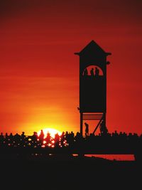 Silhouette built structure against orange sky