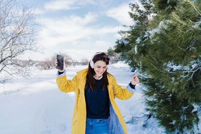 Young woman standing on snow covered tree