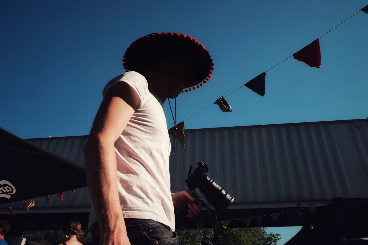 real people, lifestyles, one person, leisure activity, clear sky, casual clothing, rear view, standing, cap, outdoors, day, sky, young adult