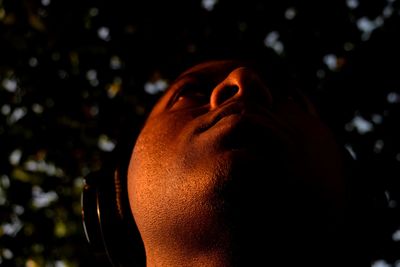 Low angle view of man listening to music against trees