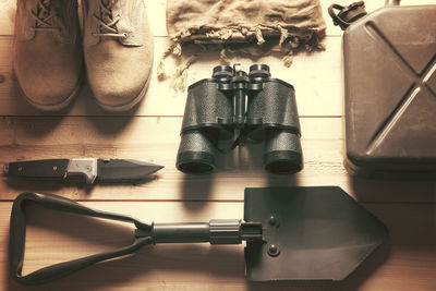 High angle view of hand tools with binoculars and boots on floor