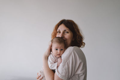 Portrait of happy mum holding infant child on hands.
