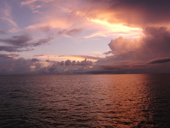 Scenic view of sea against cloudy sky during sunset