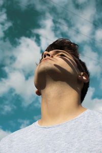 Close-up of young man looking away against sky