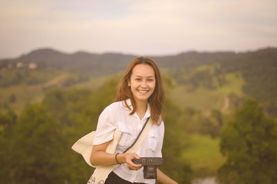 Portrait of young woman standing against mountain