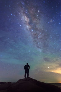 Rear view of silhouette man standing against star field at night