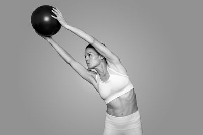 Fit woman holding a pilates ball and stretching, black and white.