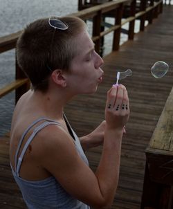 Woman blowing bubbles on wooden pier over sea