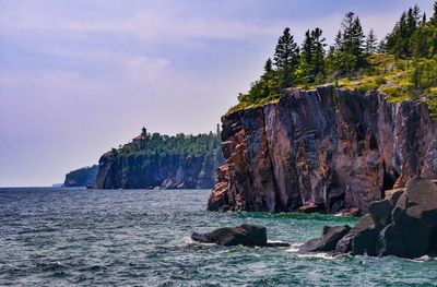 Scenic view of sea by cliff against sky