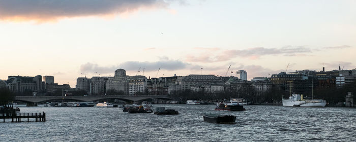 Boats in river against sky in city