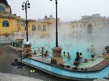 People enjoying in swimming pool against building