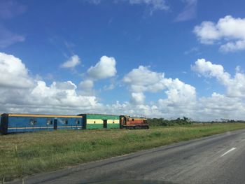 Passenger train by highway against sky seen from car windshield