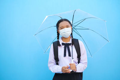 Woman holding umbrella against blue sky