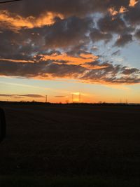 Scenic view of dramatic sky over field during sunset
