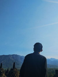 Rear view of man looking at mountain against sky